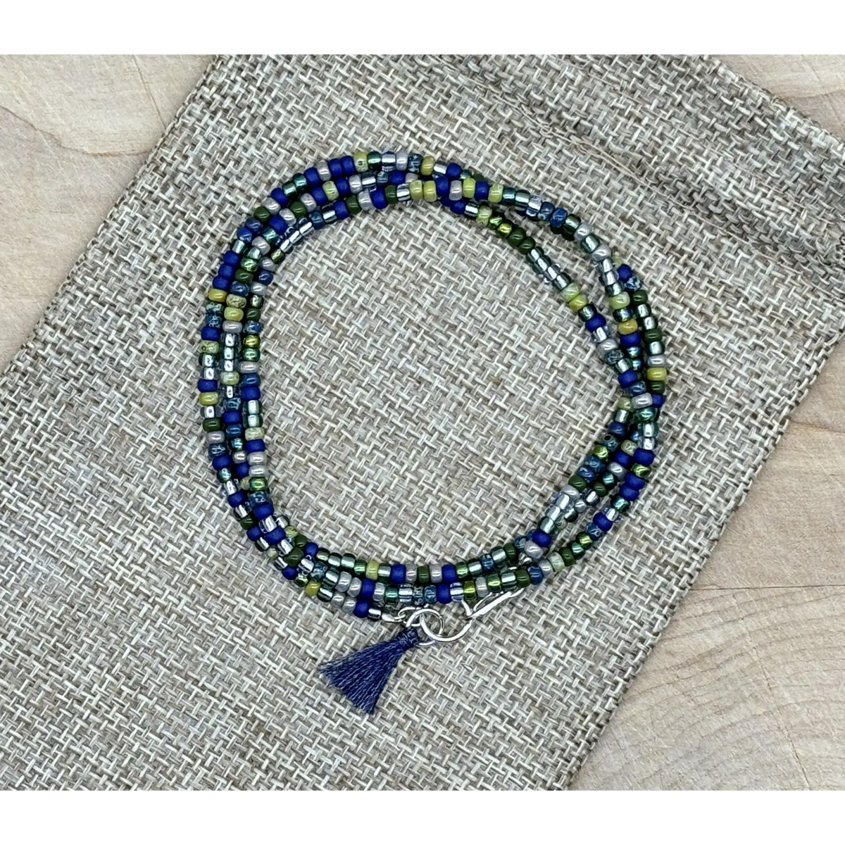 Beaded bracelet with a tassel on a textured fabric background