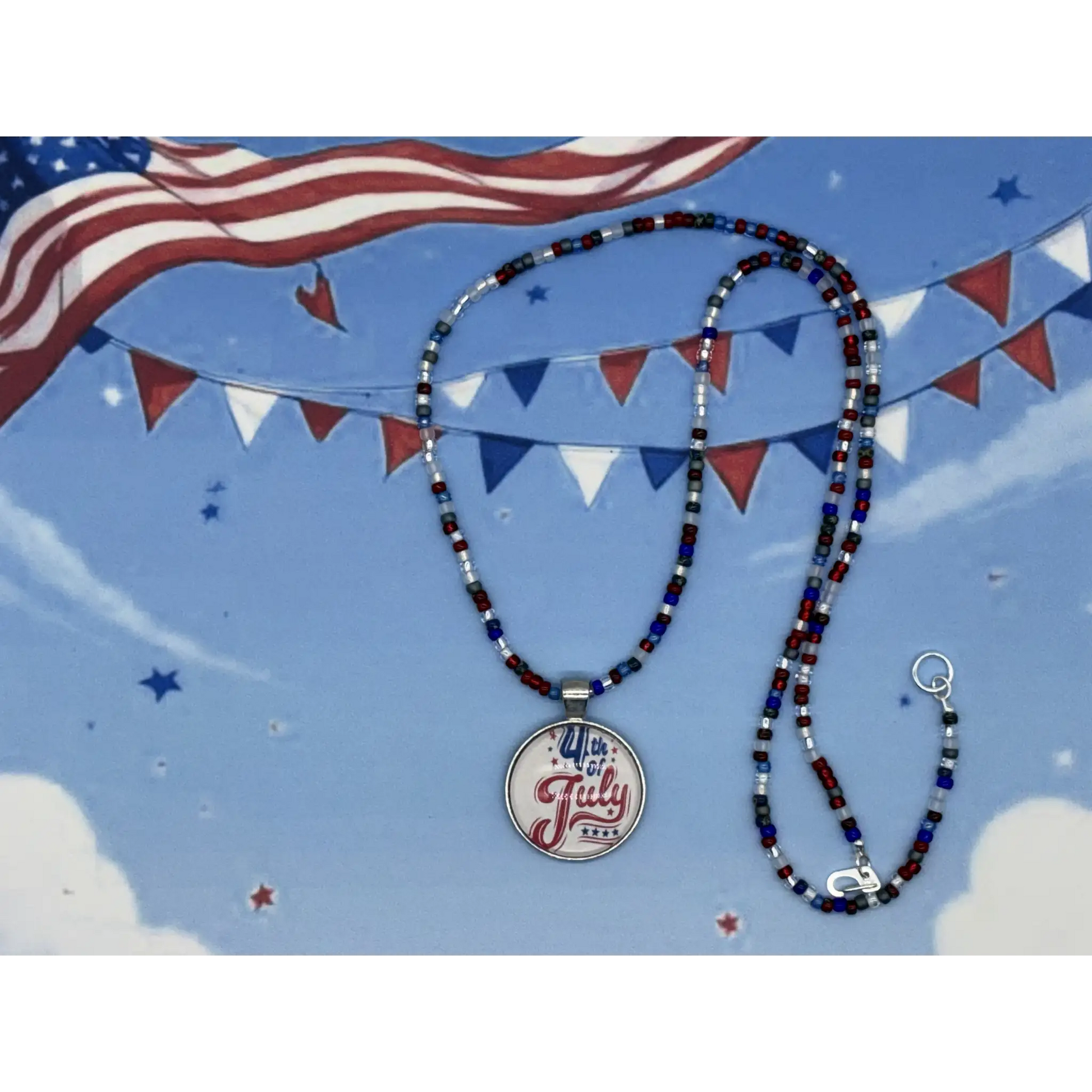 A beaded necklace with a round silver pendant reading '4th July 2025' in red and blue script, displayed against a patriotic blue background with an American flag, bunting, and stars.