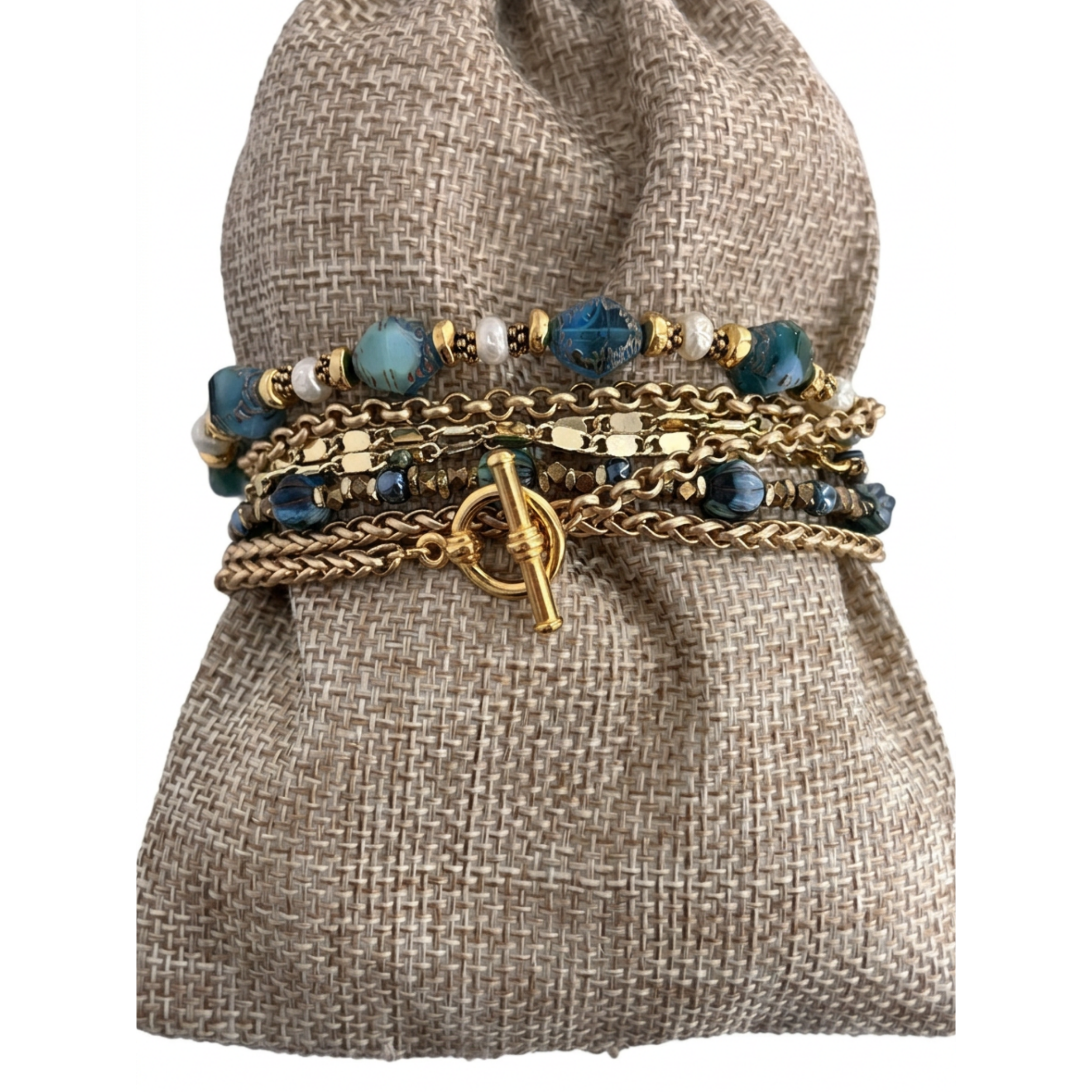 The 44-inch convertible necklace wrapped multiple times into a chunky bracelet around a rustic woven fabric pillow, showcasing the aquamarine Czech glass beads and gold toggle clasp.