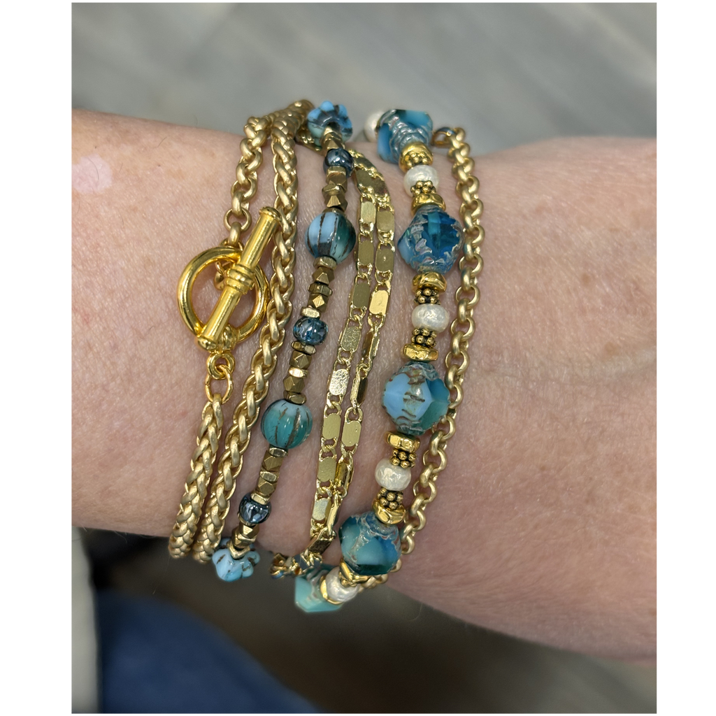 Lifestyle view of the 44-inch aquamarine and Miyuki pearl convertible jewelry piece styled as a layered multi-wrap bracelet on a person's wrist.