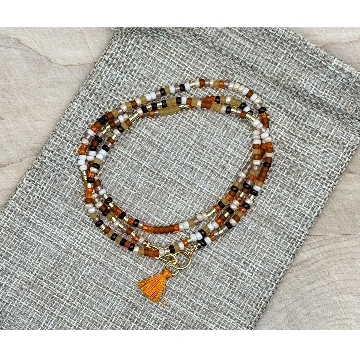 Beaded bracelet with tassel on a textured fabric surface
