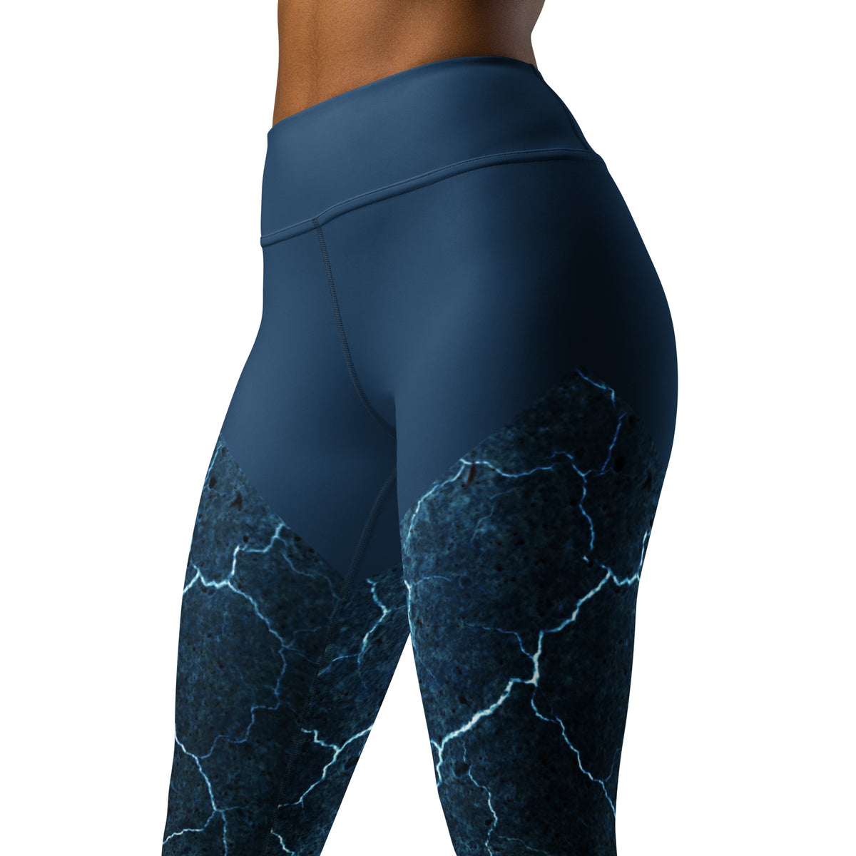Close-up of Indigo Illusion yoga leggings featuring an artistic dark blue cracked pattern with electric glowing lines on high-performance athletic fabric.