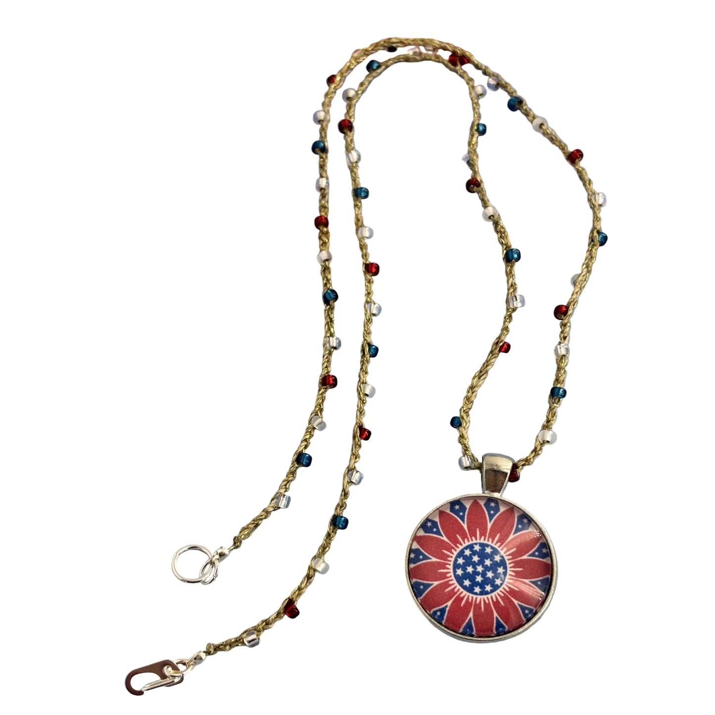 A patriotic-themed necklace featuring a round pendant with a red, white, and blue floral design, suspended on a beaded chain with small red, blue, and silver beads, displayed against a white background.