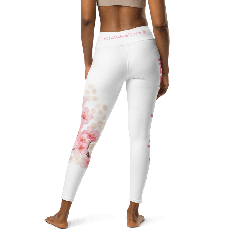 White full-length leggings with pink cherry blossom floral prints, shown on a model from a rear three-quarter angle against a white background.