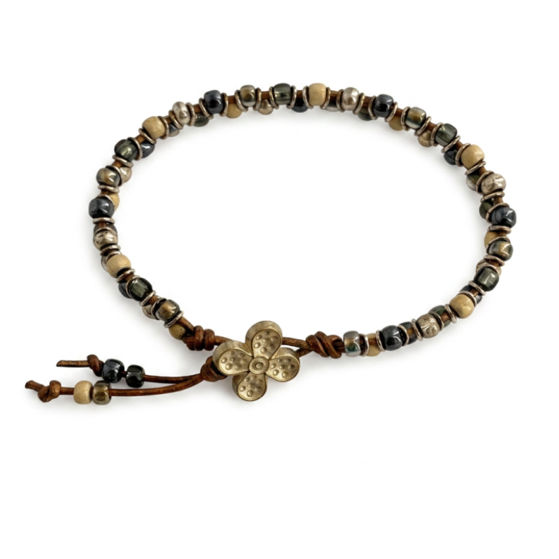 A beaded bracelet featuring Toho glass beads, and a metallic flower button, displayed on a clean white background.