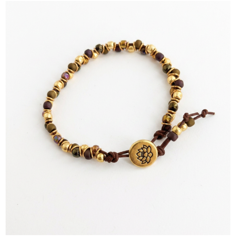 A beaded bracelet on leather cord. Featuring metallic gold and dark brown beads, with a central round gold button engraved with a lotus flower, displayed on a clean white background.