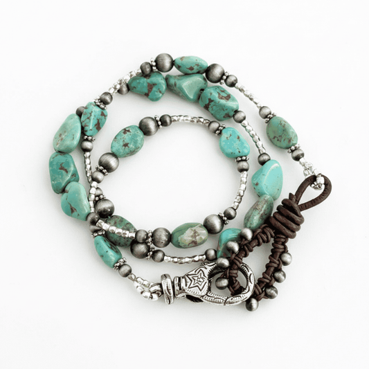 A beaded bracelet/necklace featuring turquoise nuggets, dark metallic beads, a brown leather cord loop and an ornate silver-plated lobster claw clasp, displayed on a clean white background.