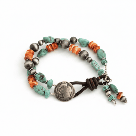 A beaded wrap bracelet featuring turquoise, orange, and dark gray beads, a dark brown cord, and a central silver-toned medallion, displayed on a clean white background.