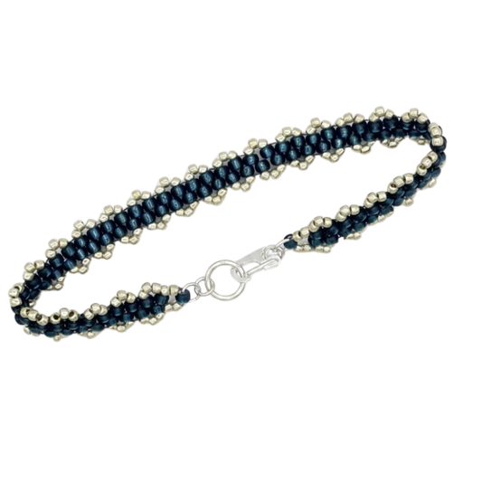A beaded bracelet featuring dark navy blue seed beads woven with rows of small, metallic silver beads, finished with a silver lobster clasp.