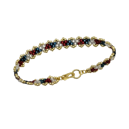 A beaded bracelet with a gold-plated clasp, featuring repeating patterns of gold, white, navy blue, and burgundy red beads, shown on a plain white background.