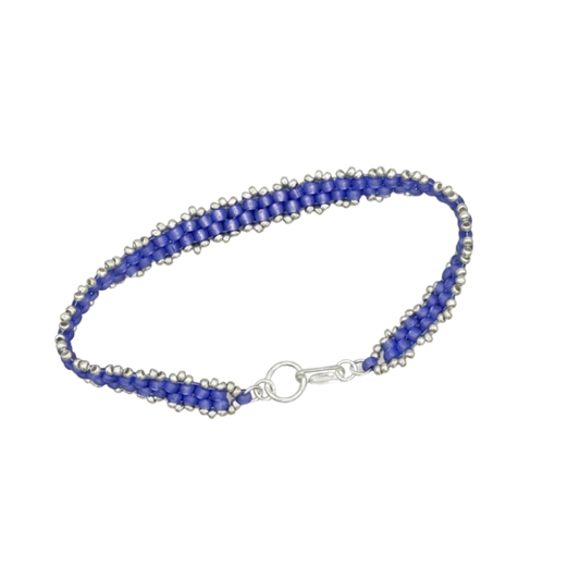 A beaded bracelet with violet seed beads and silver-toned beads, featuring a silver lobster clasp closure, shown on a plain white background.