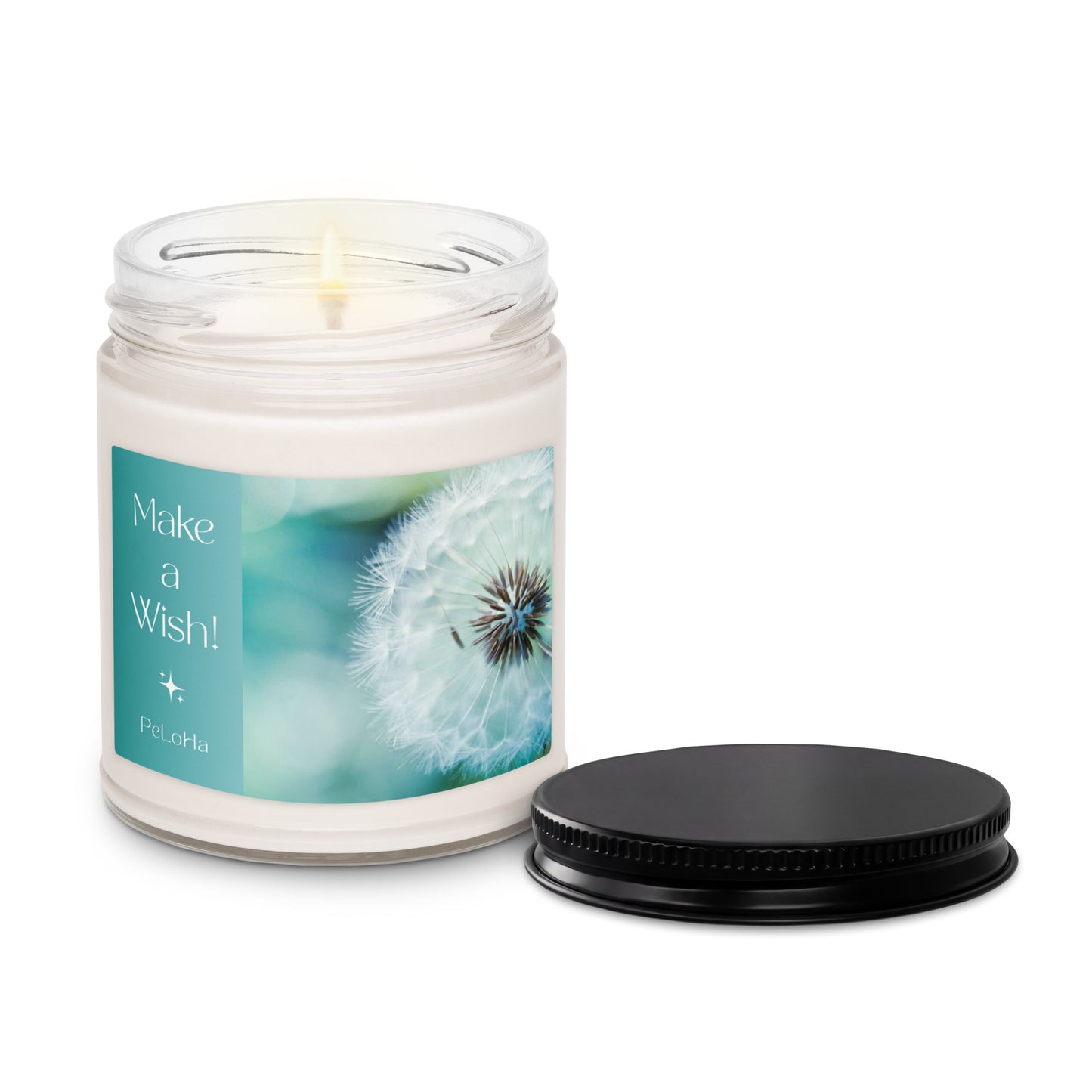 A lit jar candle with a clear glass container, white wax, and a printed label reading 'Make a Wish!' with a dandelion photo. The black metal lid is placed beside the candle on a clean white background.