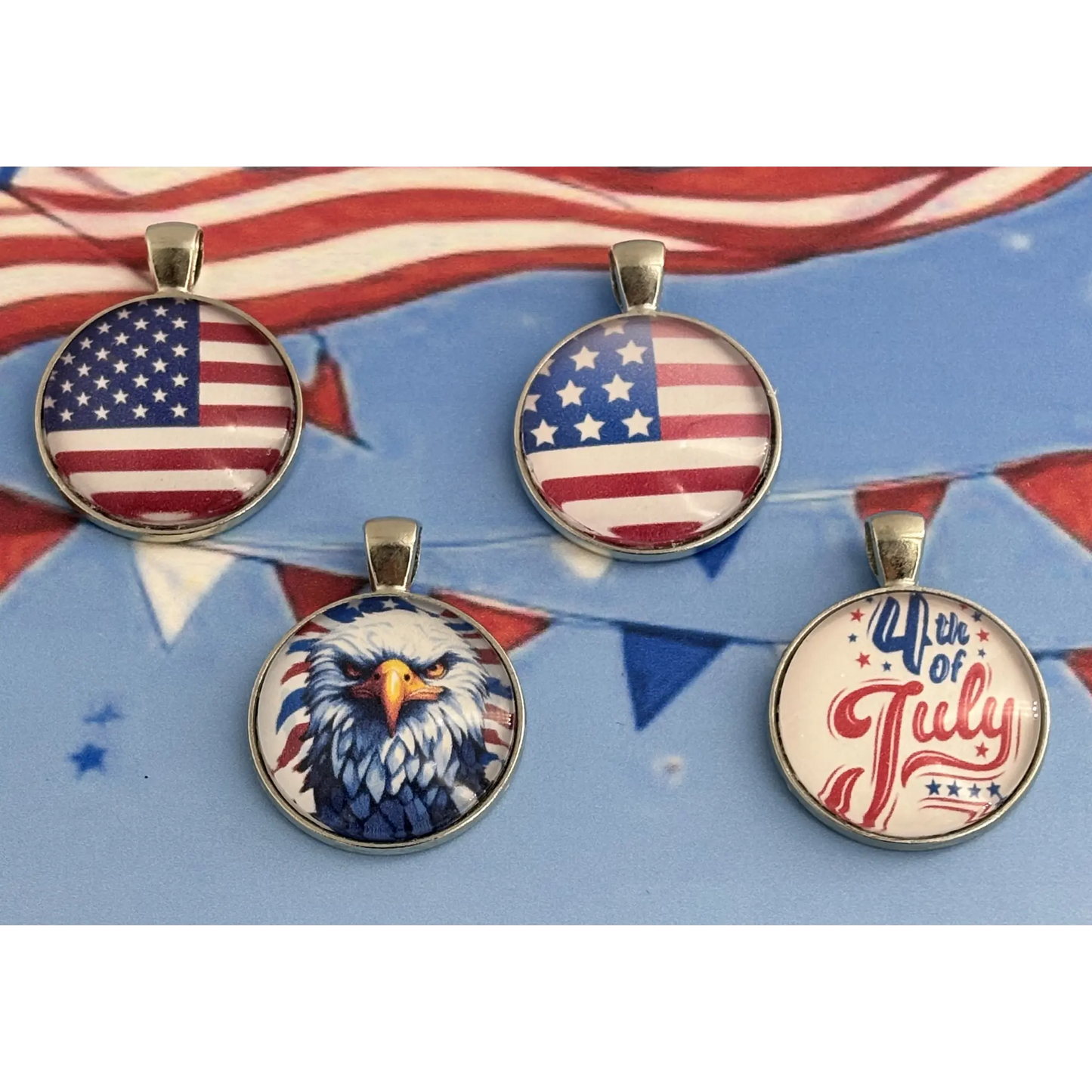 Four round pendants with patriotic designs, including two with the American flag, one with a bald eagle, and one reading '4th of July', displayed on a blue background with red and white bunting.
