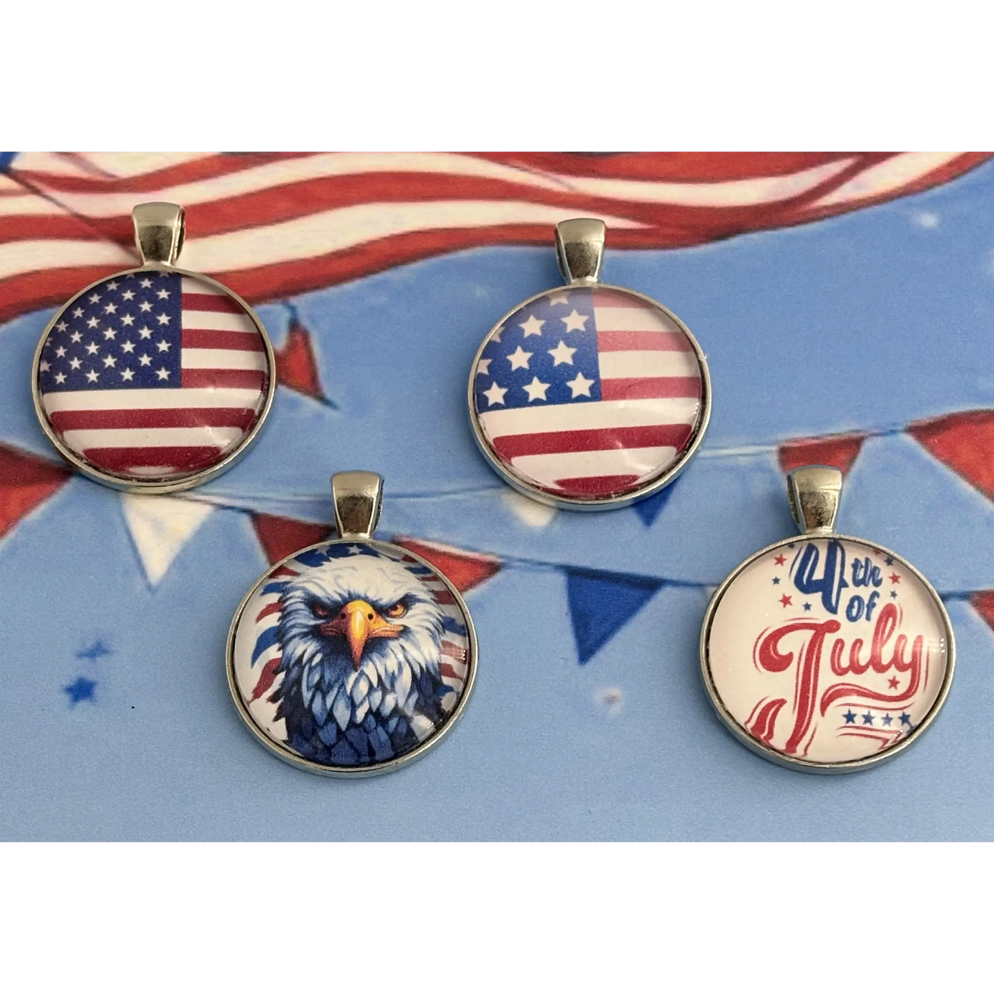 Four round pendants with patriotic designs, including two with the American flag, one with a bald eagle, and one reading '4th of July', displayed on a blue background with red and white bunting.